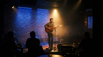 Acoustic singer on small venue stage under spotlight